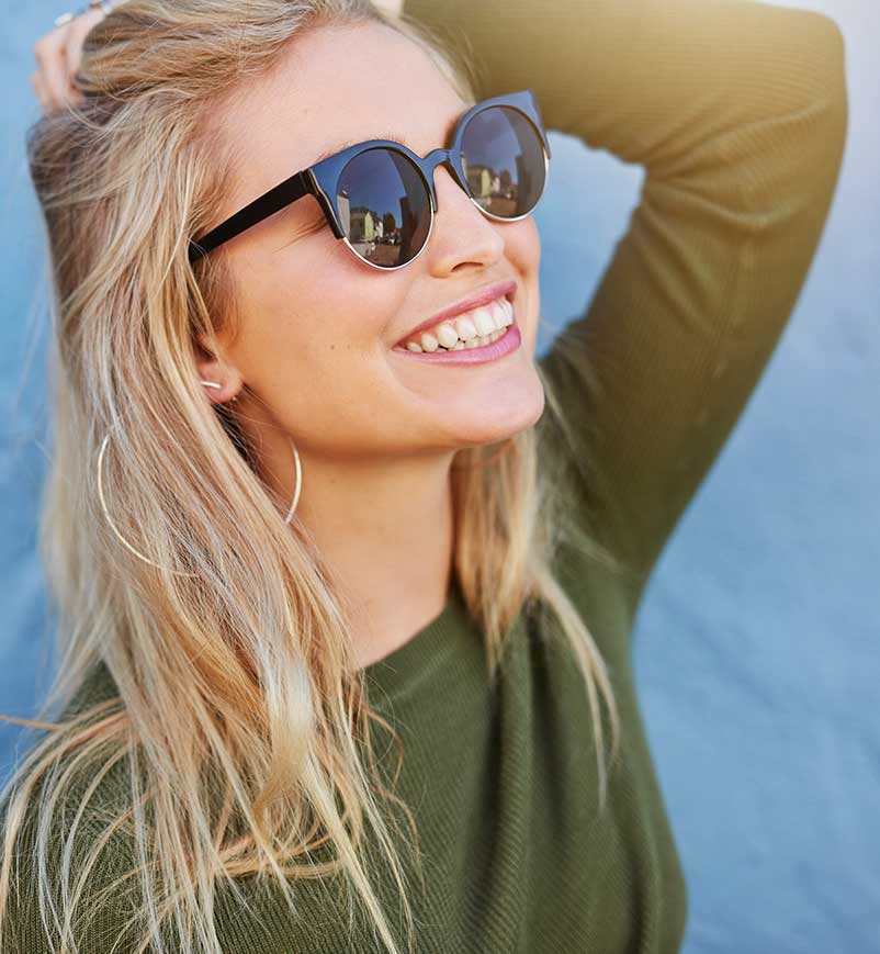 Young lady with sunglasses smiling in the sun