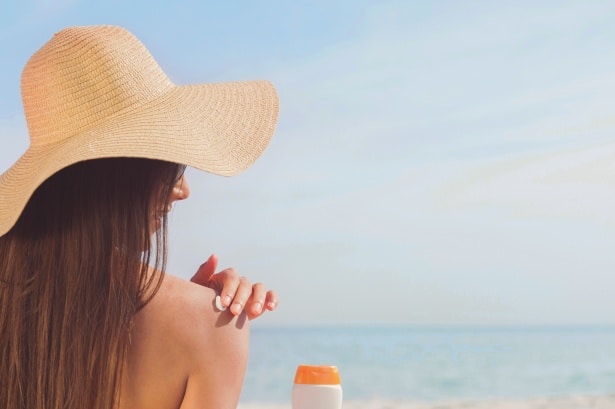 sunscreen woman putting sunscreen on her back