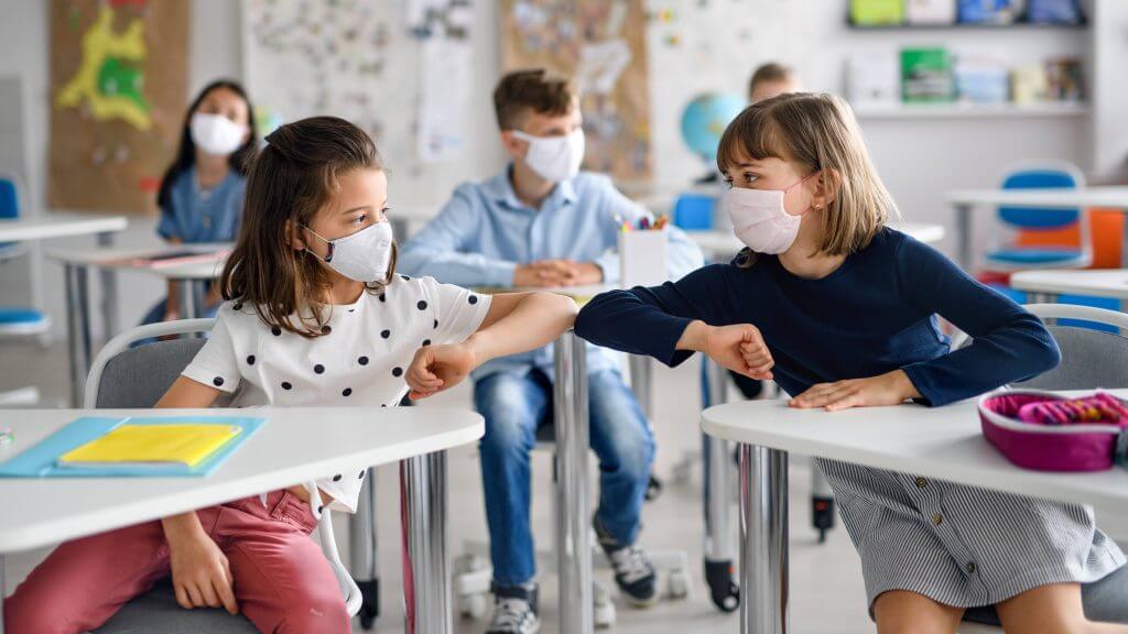 a-classroom-of-elementary-or-middle-school-aged-children-wearing-masks-and-praticing-social-distancing-touching-elbows